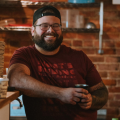 Jackson Bredehoft, co-owner of Café Rica, a family-owned coffee company and café in Battle Creek standing at the cafe's cash wrap.